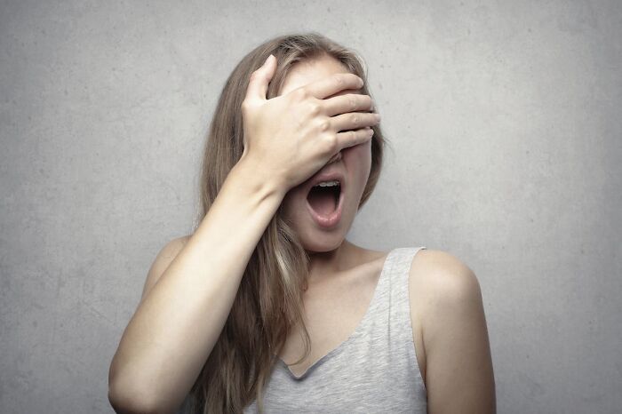 Woman covering her eyes with one hand, expressing surprise or curiosity, representing questions women ask men.